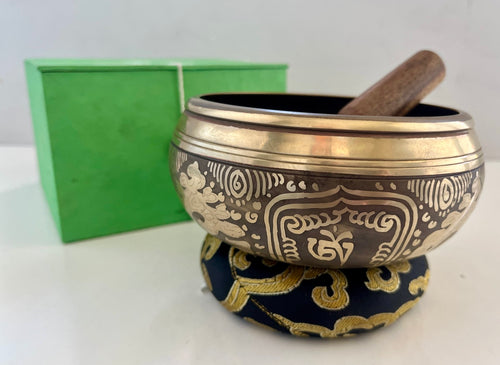 Singing bowl. A wooden striker is also visible resting on the bowl.