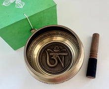 Load image into Gallery viewer, Brass singing bowl with OM symbol and wooden mallet on a white background

